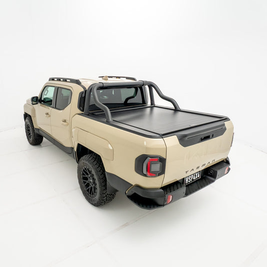 Angled rear view of a Kia Tasman fitted with an HSP Roll R electric roller cover in the closed position with black sports bars mounted behind the cab.
