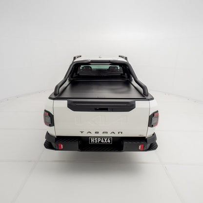 Straight rear view of a Kia Tasman fitted with the HSP Roll R electric roller cover, showing the closed aluminium roller shutter and integrated rear handle above the tailgate.