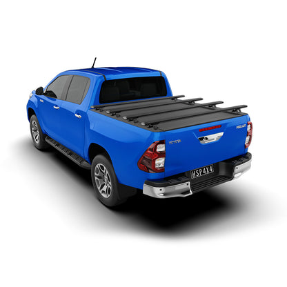 Blue Toyota Hilux SR5 with HSP roller cover closed and four load bars fitted rear three-quarter studio image