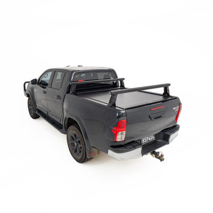 HSP Load Rack JNR fitted to black Toyota Hilux dual cab, rear three quarter view showing compact ladder rack over open tub fitted with a HSP Roller Cover