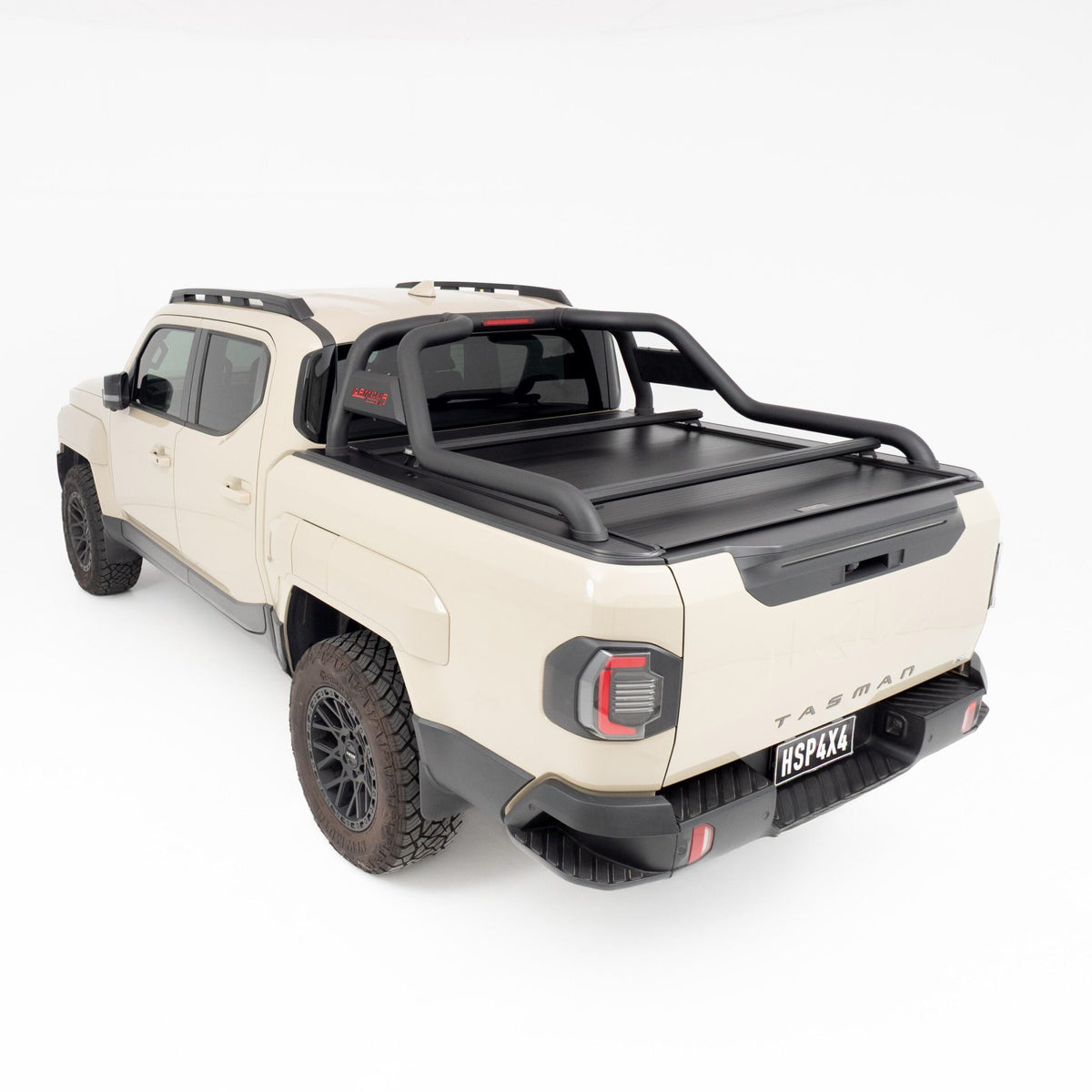 Rear three quarter view of a cream Kia Tasman with HSP Load Bars, closed HSP Roll R Cover, and a tub mounted sports bar.